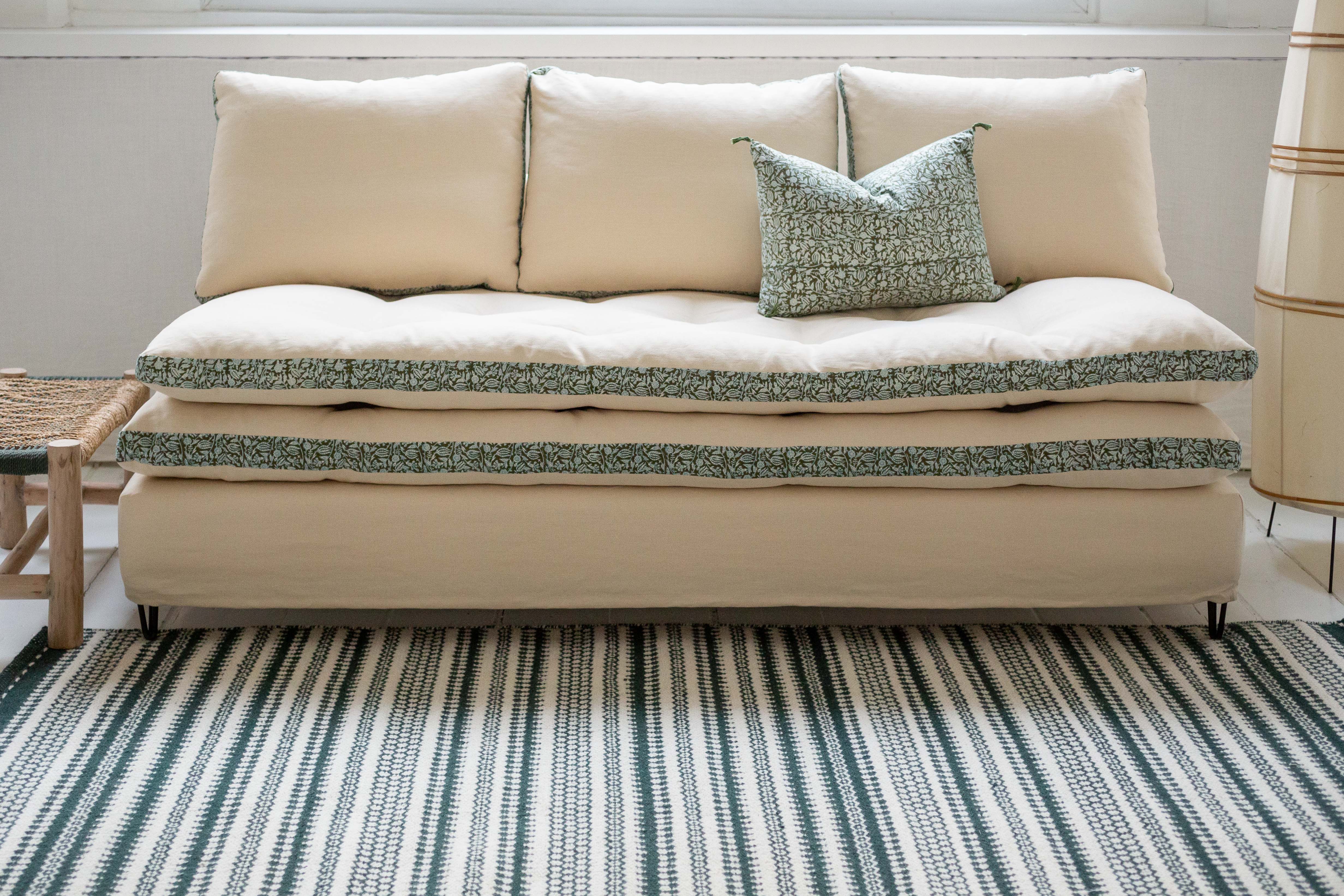 Canapé blanc avec des imprimés végétaux verts autour des coussins