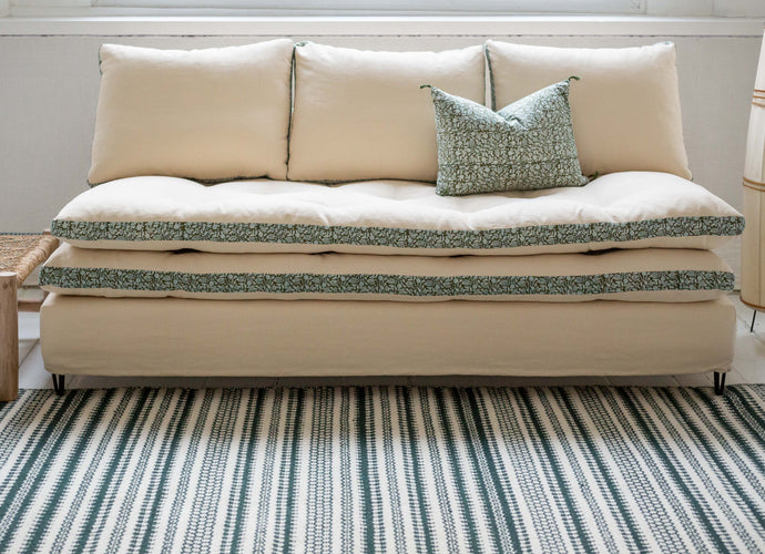 Canapé blanc avec des imprimés végétaux verts autour des coussins