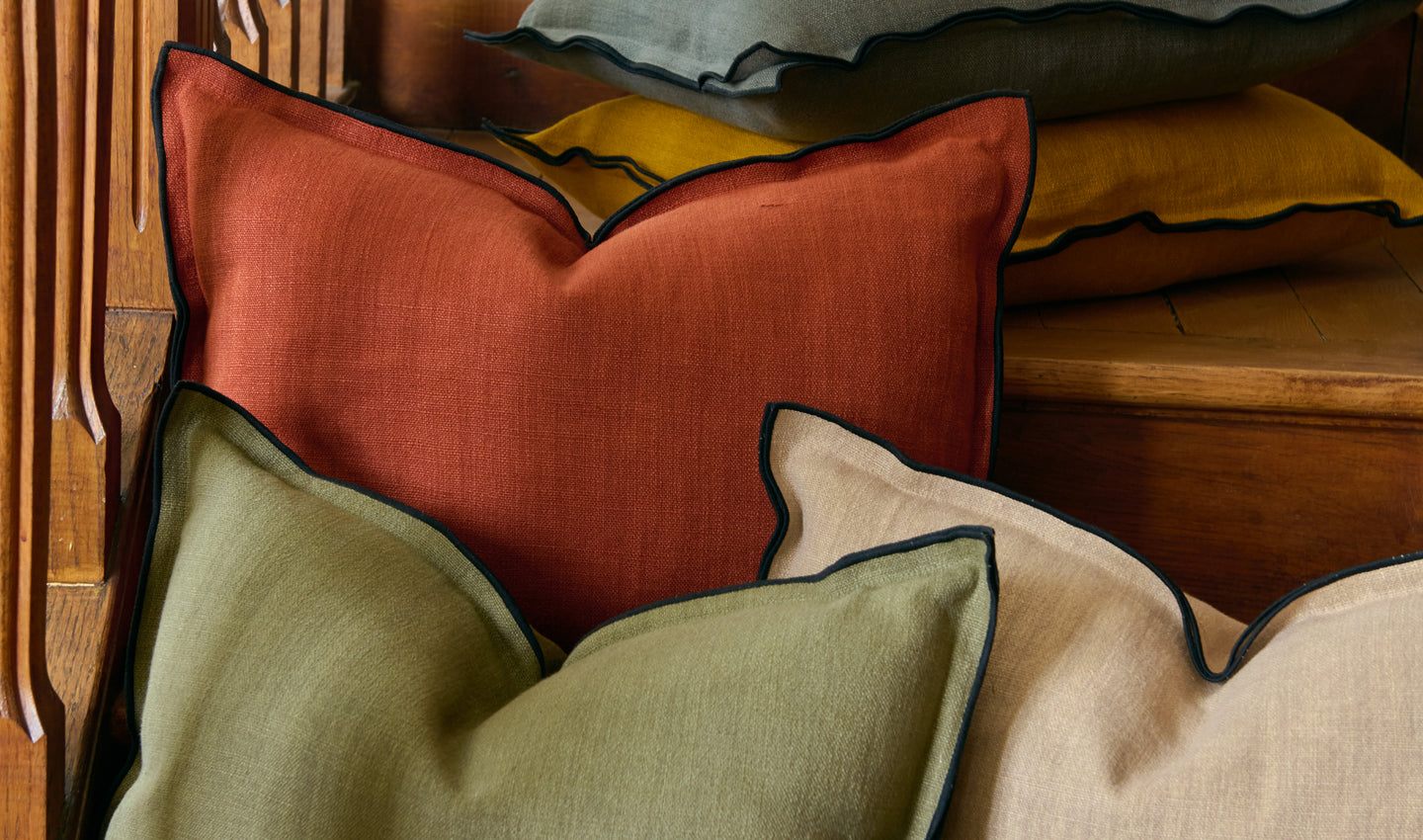 Ensemble de sept coussins en lin Gareth colorés avec un bourdon noir