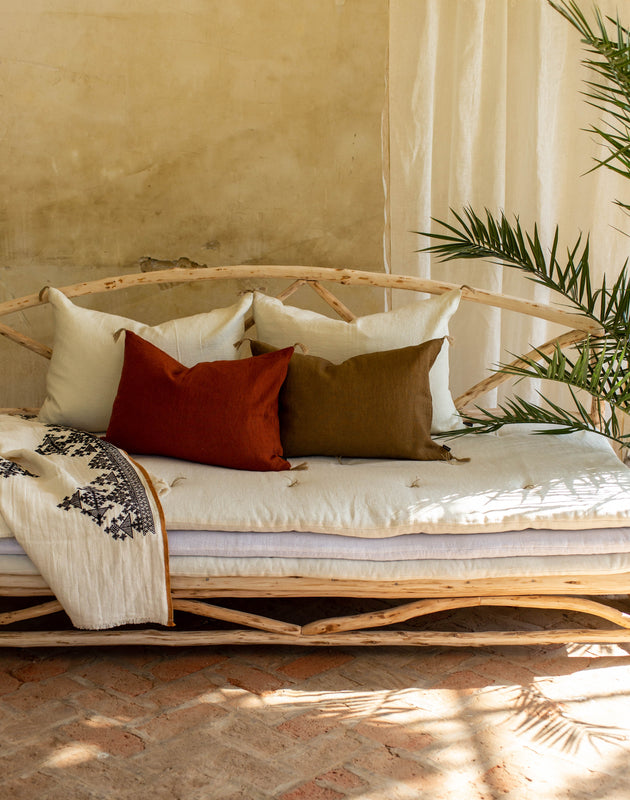 Ensemble de quatre coussins Luni en lin disposés sur un divan.