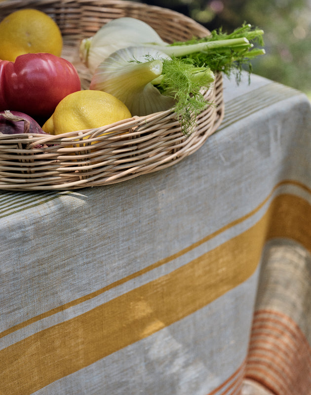 Détail des rayures de la nappe Soleo en lin sur laquelle est posée la cloche Salva en osier