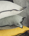 Housse de coussin en lin avec un bord noir en blanc, sauge et moutarde