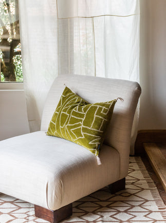 Un coussin Jody couleur Citrine posé sur un fauteuil chauffeuse Pacha