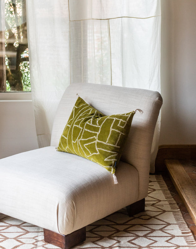 Un coussin Jody couleur Citrine posé sur un fauteuil chauffeuse Pacha