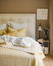 Chambre épuré avec un linge de lit jaune et blanc